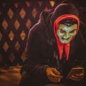 person in black and red mask holding smartphone